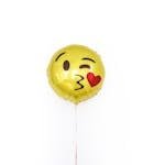 Golden glossy round shaped balloon with smiley kissing heart face filled with helium arranged on white background isolated in studio